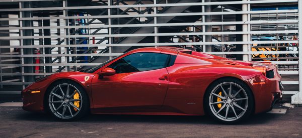 A sleek red Ferrari supercar elegantly parked outdoors, showcasing luxury design. Voitures 4K