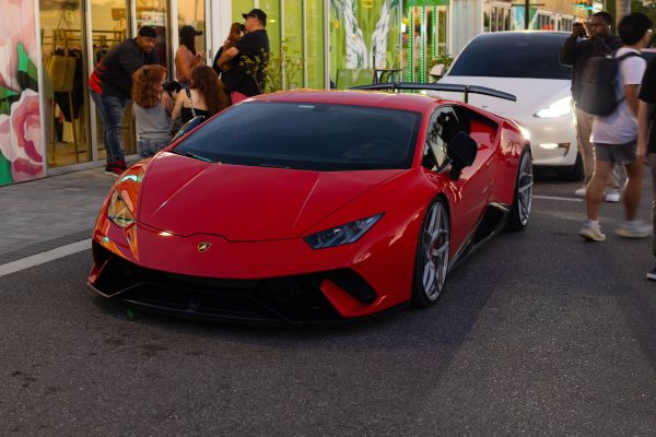 A sleek red Lamborghini Huracan displayed at a bustling outdoor car meet. Voitures 4K