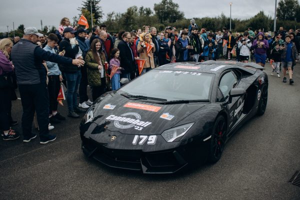 A sleek sports car draws a huge crowd during an exciting racing event, showcasing energy and excitement. Voitures 4K