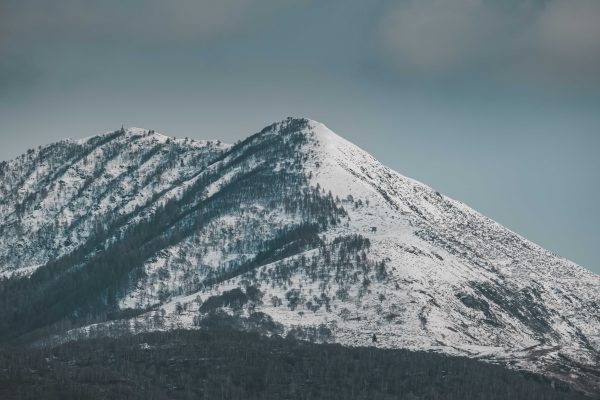 A snow-covered mountain peak with a cloudy sky, captured in a serene winter landscape. Nature 4K