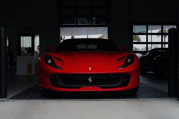 A striking red sports car parked in a contemporary garage setting, showcasing luxury design. Voitures 4K