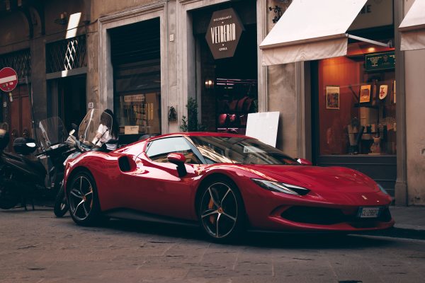 A striking red supercar parked along a charming street in Florence, Italy, showcasing urban elegance. Voitures 4K