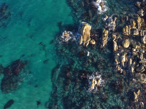 A stunning aerial shot of a rocky coastline with vibrant turquoise waters, showcasing natural beauty and tranquility. Nature 4K