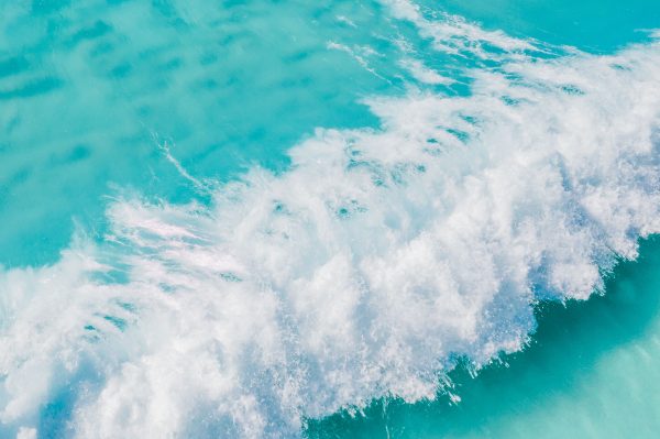 A stunning aerial shot of turquoise waves crashing in the vast ocean, creating a dynamic and vibrant natural scene. Nature 4K