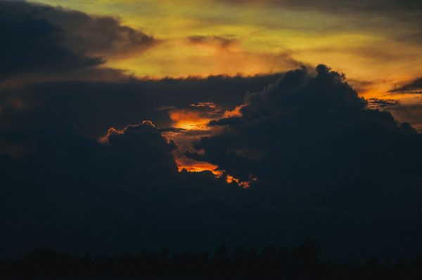 A stunning and dramatic sunset with vibrant skies and dark clouds forming a dramatic scene. Dark 4K