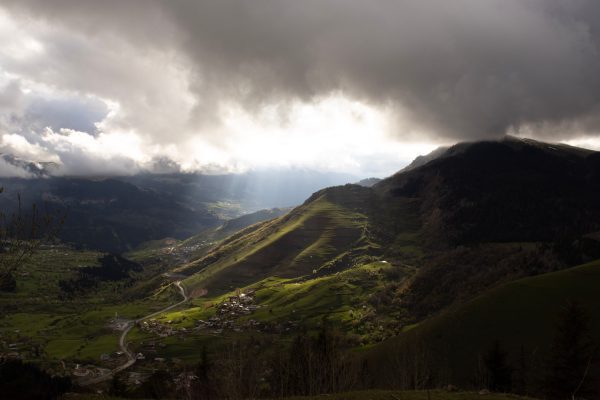 A stunning mountain valley scene with dramatic clouds and sunbeams breaking through. Nature 4K