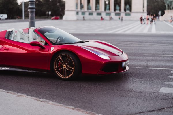 A stunning red Ferrari supercar captured on a city street, showcasing sophistication and speed. Voitures 4K