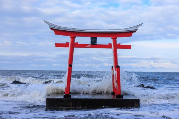 A stunning red torii gate stands amid crashing waves in Shosambetsu, Japan. Anime 4K