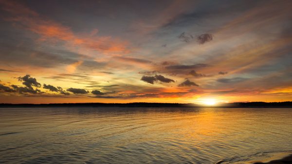 A stunning sunset over a calm ocean with vibrant, colorful skies, capturing a serene and peaceful moment. Nature 4K