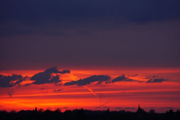 A stunning sunset with vivid oranges and silhouettes, creating a dramatic evening landscape. Nature 4K