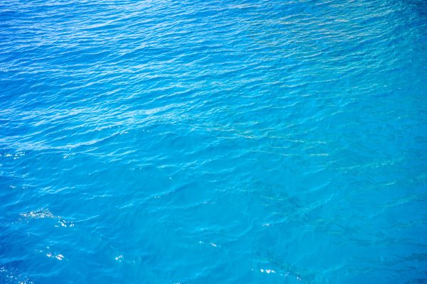 A stunning top view of vibrant blue ocean waters with gentle waves rolling on a sunny day. Nature 4K