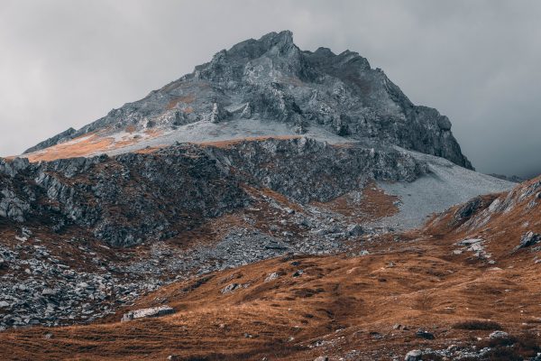 A stunning view of a rugged, rocky mountain landscape with a moody, cloudy sky. Nature 4K