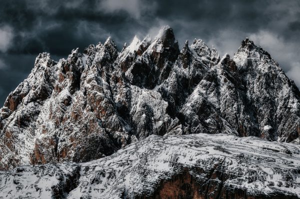 A stunning view of rugged, snow-covered mountain peaks under a dramatic cloudy sky. Nature 4K