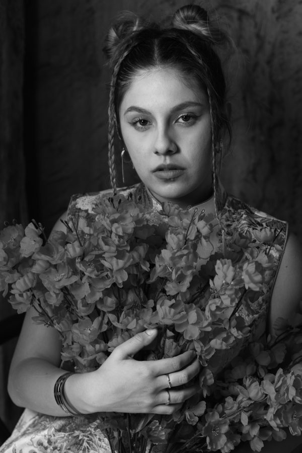 A stylized black and white portrait of a woman holding a bouquet of flowers, captured indoors, conveying a classic and artistic mood. Mobile 4K