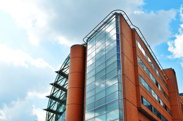 A tall, modern building with glass windows reflecting the sky, showcasing urban architecture. Architecture 4K