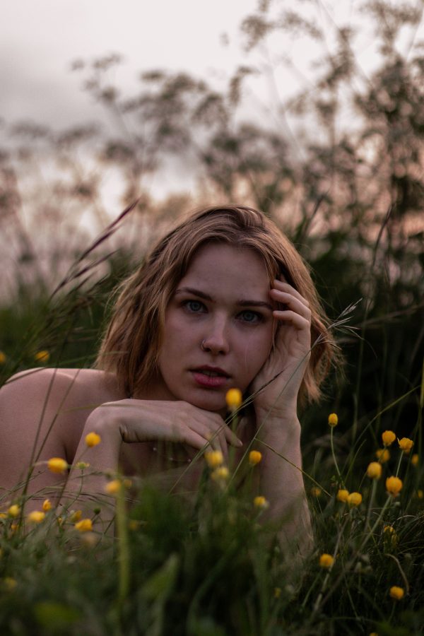 A tranquil portrait of a woman surrounded by flowers in a meadow at sunset. Mobile 4K
