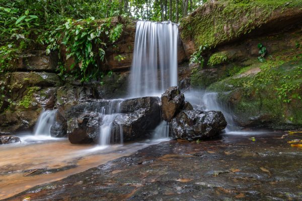A tranquil waterfall cascading over rocks surrounded by lush greenery in Costa Rica's tropical jungle. Nature 4K