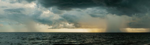 A vast ocean under stormy skies with dramatic dark clouds and rainfall. Dark 4K