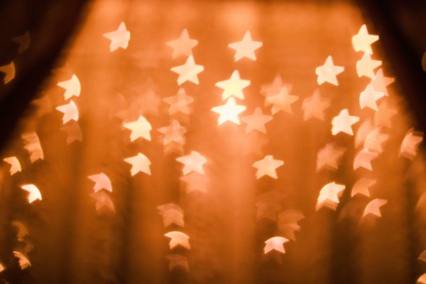 A warm, blurred star bokeh effect providing a festive abstract background. Espace 4K