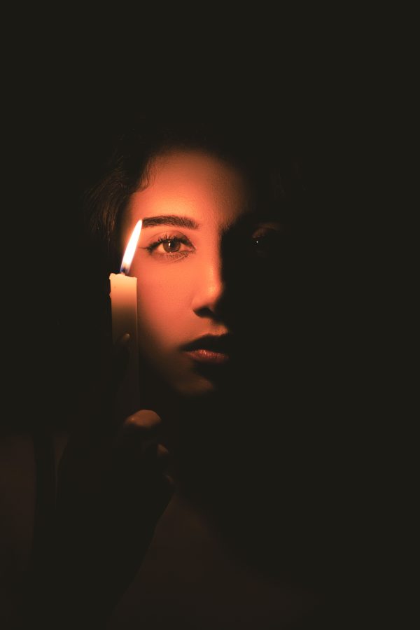 A woman holding a candle in darkness, casting a soft, mysterious glow. Mobile 4K