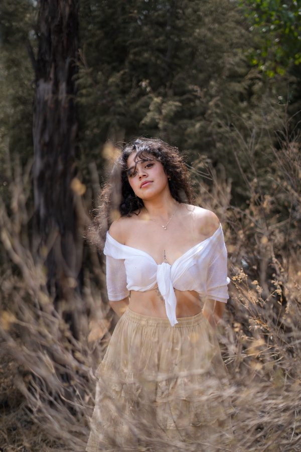 A woman in a white blouse poses gracefully in an outdoor nature setting. Mobile 4K
