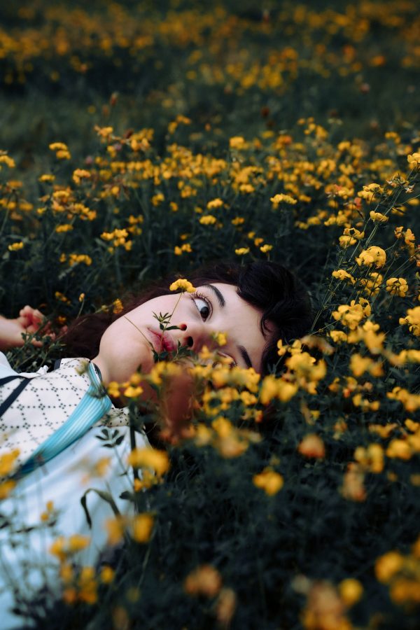 A woman lies in a field of yellow flowers captured with moody tones in Düsseldorf. Mobile 4K