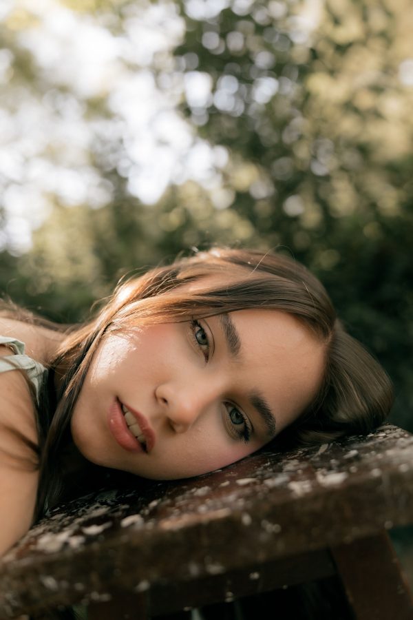 A woman lying on a bench outdoors, bathed in gentle sunlight. Mobile 4K
