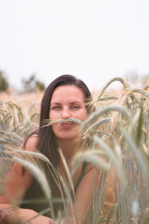 A woman playfully poses amidst golden wheat, embodying rural charm and natural beauty. Mobile 4K