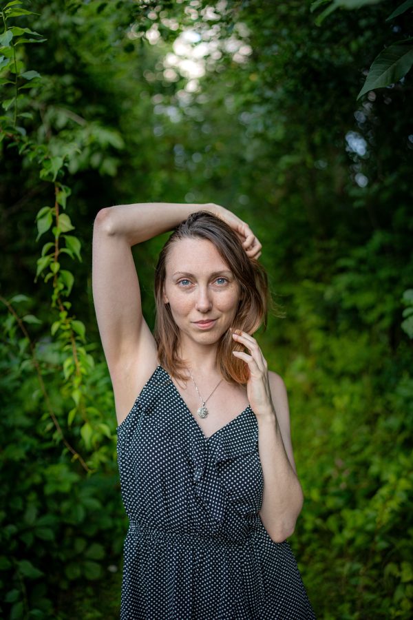 A woman poses confidently in a forest, surrounded by lush greenery. Mobile 4K