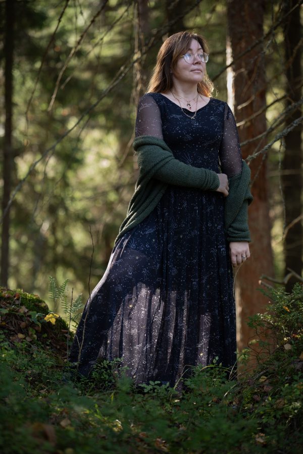 A woman stands in a sunlit forest, exuding elegance in a long dress. Mobile 4K