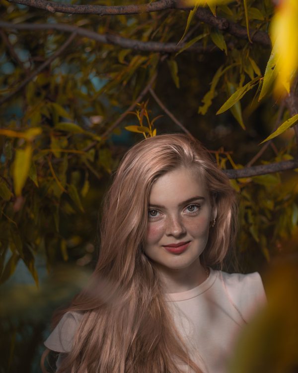 A young woman with long hair amid lush foliage, embracing natural beauty. Mobile 4K