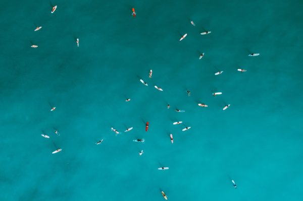 Aerial shot capturing surfers on turquoise ocean water, emphasizing outdoor leisure and water sports. Nature 4K