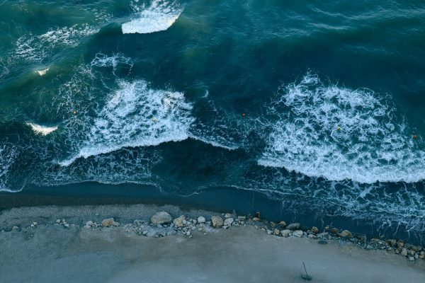 Aerial shot of ocean waves crashing against a rocky shoreline, creating beautiful foam patterns. Nature 4K