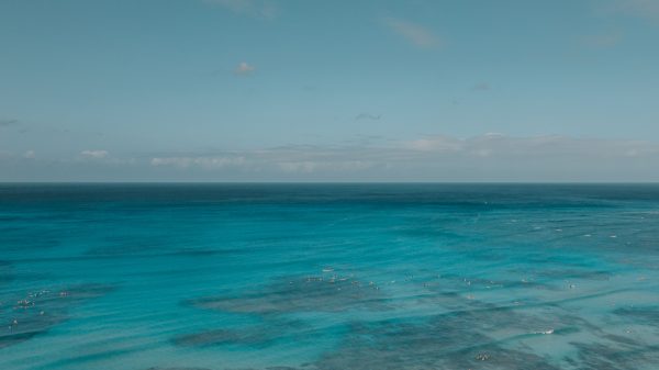 Aerial view capturing a serene blue ocean with a calm horizon and scattered clouds. Nature 4K