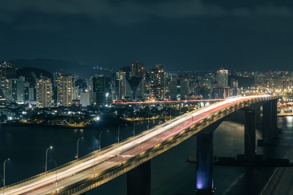Aerial view of a lit-up city bridge showing light trails against a vibrant urban skyline at night. Architecture 4K