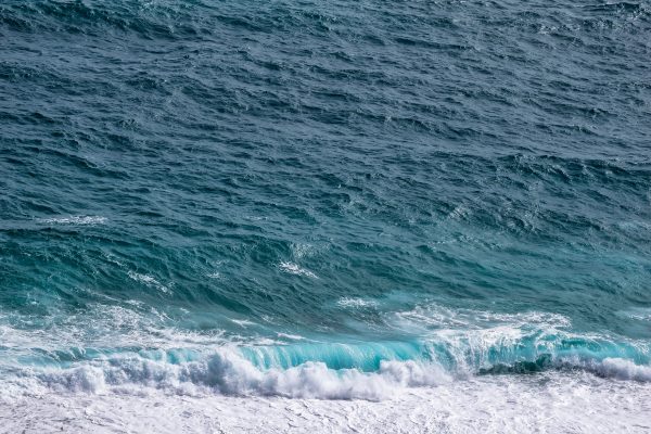 Aerial view of ocean waves crashing on the shore, showcasing blue and turquoise hues. Nature 4K