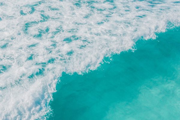 Aerial view of vibrant turquoise ocean waves crashing on the shore, capturing the beauty and energy of the sea. Nature 4K