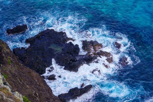 Aerial view of waves crashing on a rocky shoreline, creating dramatic foam and splash in the ocean. Nature 4K