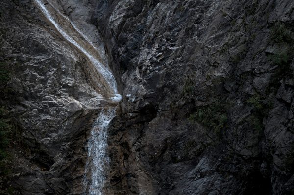 An impressive waterfall flowing down a rugged rocky cliff in a serene natural setting, emphasizing its natural beauty. Nature 4K