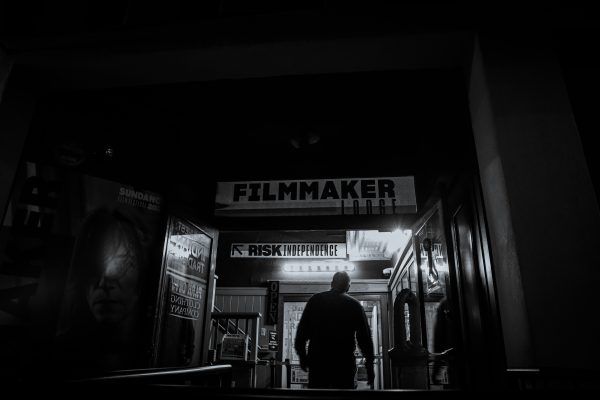 An individual enters a filmmaker-themed building at night, evoking a mysterious artistic vibe. Dark 4K