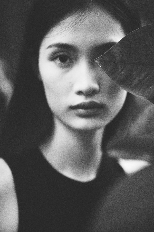 Artistic black and white portrait capturing a woman's contemplative gaze amidst nature. Mobile 4K