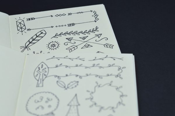 Artistic black doodles on white paper, featuring arrows and nature elements. Manga 4K