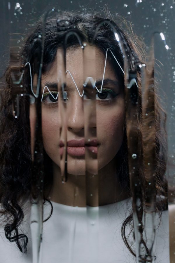 Artistic close-up of a woman with wet glass in focus, capturing emotion. Mobile 4K