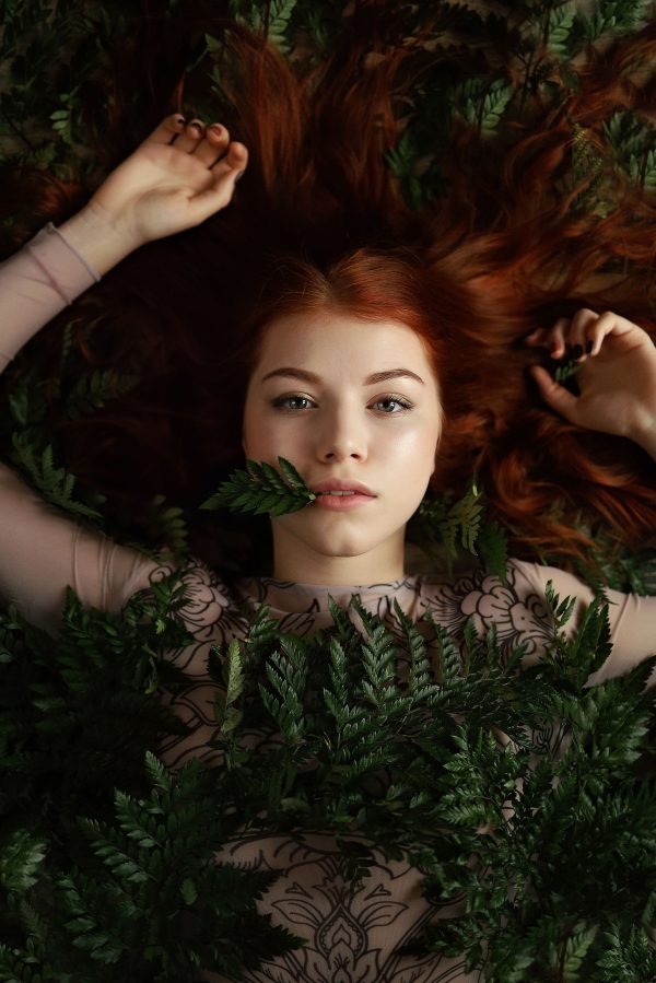 Artistic overhead portrait of a woman surrounded by lush ferns, exuding a mystical and natural vibe. Mobile 4K