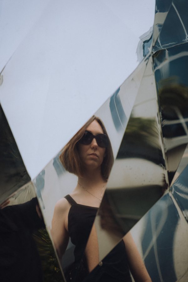 Artistic portrait of a woman reflected in geometric mirrors wearing sunglasses. Mobile 4K