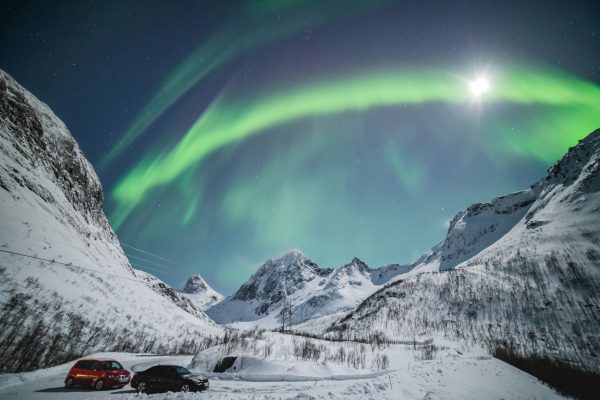 Aurora Borealis illuminates snowy peaks in Troms og Finnmark, Norway, under a starry sky. Espace 4K