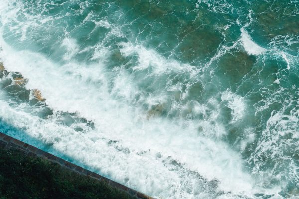Beautiful aerial view of turquoise sea waves crashing on the rocky shore of Piran, Slovenia. Nature 4K