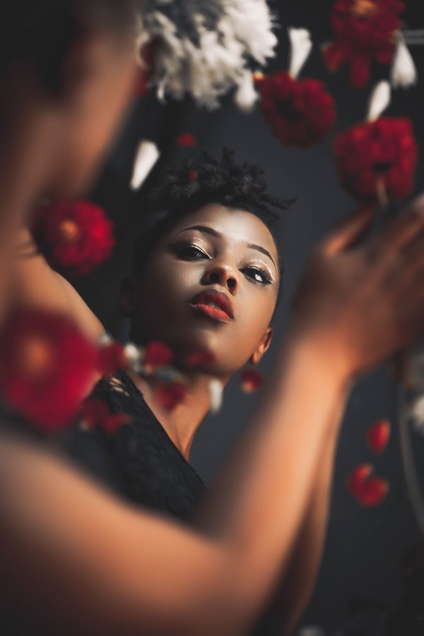 Beautiful studio portrait of a woman surrounded by vibrant red flowers. Mobile 4K