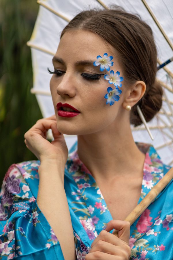 Beautiful woman with blue floral makeup in kimono holding umbrella outdoors in Mexico City. Mobile 4K