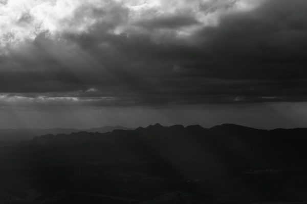Black and white landscape of dramatic clouds casting shadows over mountains in Minas Gerais, Brazil. Dark 4K
